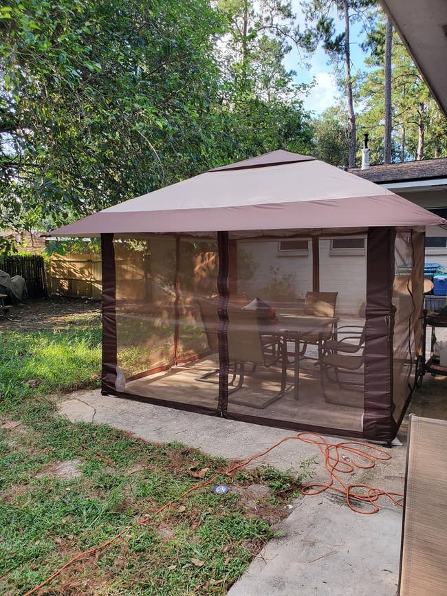 Backyard gazebo with sheer curtains over a patio set, suitable for outdoor dining and relaxation