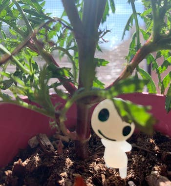 Small white figurine nestled in a potted plant 