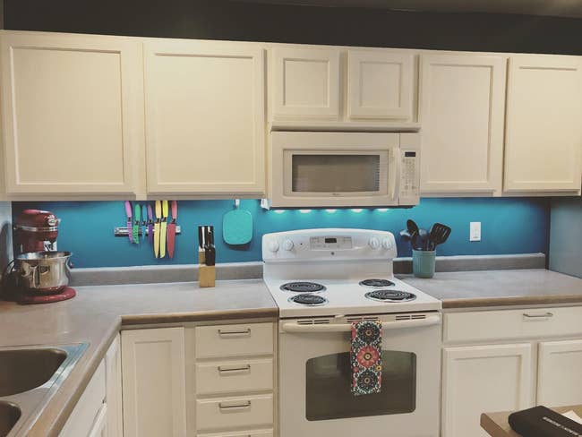 Kitchen with white cabinets, an electric stove, and various appliances on the counter