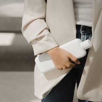 Model holding rectangular flat version of white bottle 