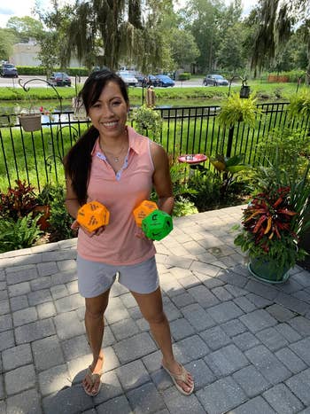 reviewer holds two orange dice and one green dice with different exercise movements on each