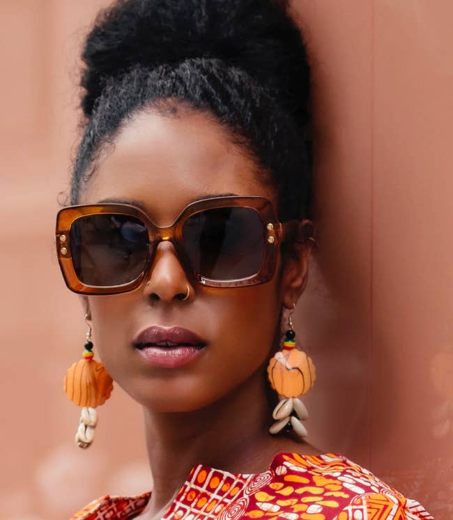 woman in orange statement drop earrings