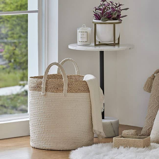 Photo of the half white and half wicker basket on floor, filled with blankets