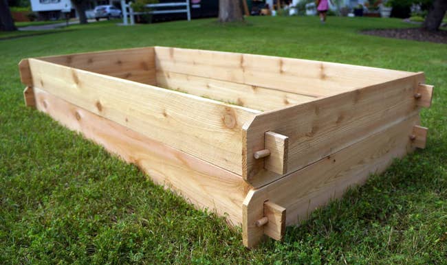 a natural wood raised garden sitting in grass