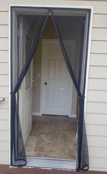reviewer's mesh curtains over an open door frame and the curtains are hanging open with hooks
