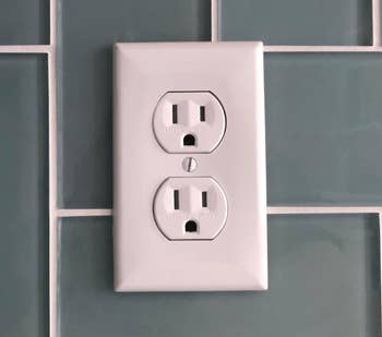 An electrical outlet on a tiled wall