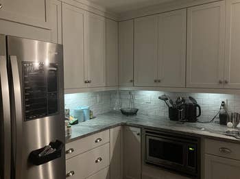 A modern kitchen with stainless steel appliances, white cabinetry, and a tiled backsplash