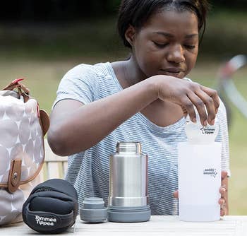 parent putting bottle inside warmer at park