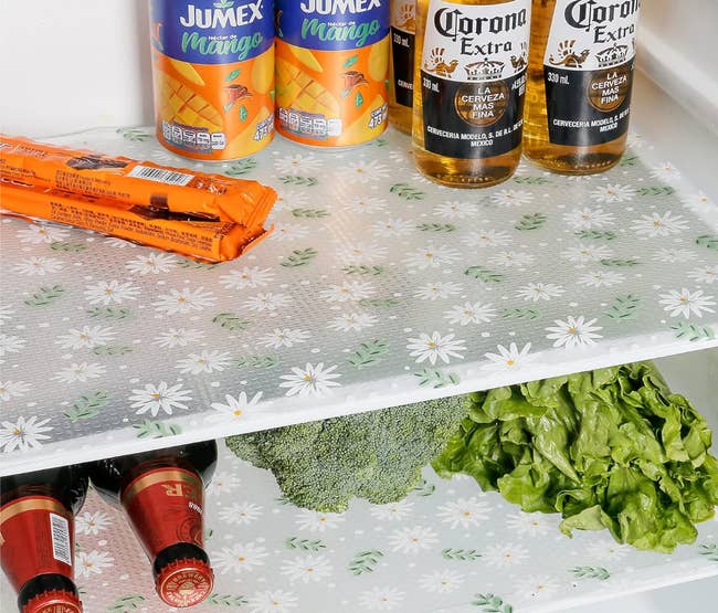 Fridge shelves lined with a transparent liner with a white and green leaf and daisy print 