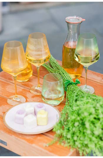 Elegant glassware on a table with a pitcher and a plate of pastries amidst fresh greenery