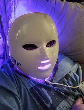 reviewer wearing glowing LED light therapy face mask