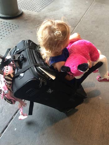 reviewer showing a small child sitting in thee seat attached to a suitcase