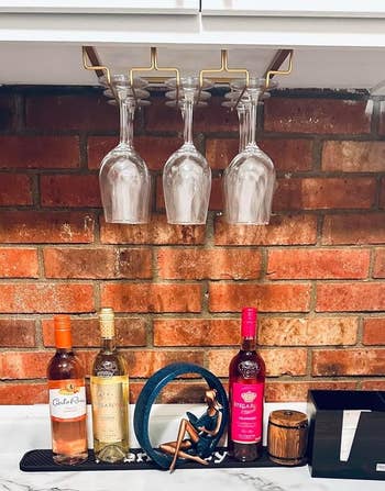 reviewer's gold stemware rack under a cabinet holding glasses