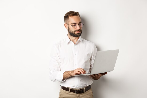 Biznes. Poważny menedżer pracuje na laptopie, stoi