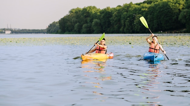 Bezpłatne zdjęcie dwa mężczyzna paddles kajak na spokojnym jeziorze