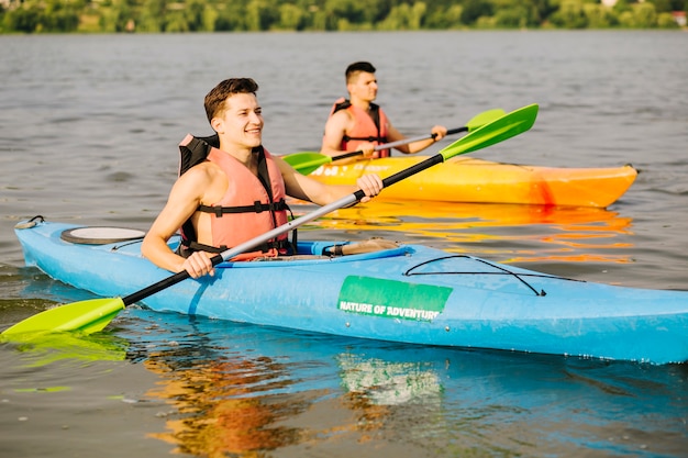 Bezpłatne zdjęcie dwa szczęśliwa samiec kayaking na rzece