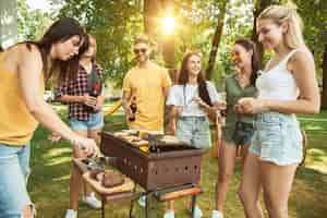 Bezpłatne zdjęcie grupa szczęśliwych przyjaciół o piwo i grill party w słoneczny dzień. odpoczynek razem na świeżym powietrzu na leśnej polanie lub podwórku