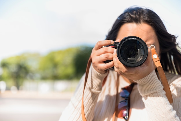 Bezpłatne zdjęcie kobieta bierze fotografię podczas dnia z plamy tłem