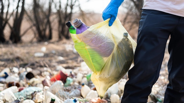 Bezpłatne zdjęcie mężczyzna zbiera z ziemi porozrzucane plastikowe butelki