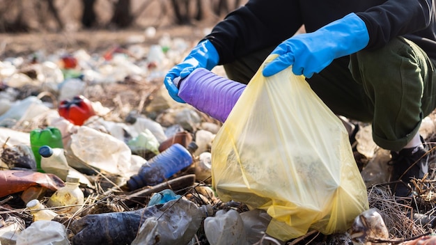 Bezpłatne zdjęcie mężczyzna zbiera z ziemi porozrzucane plastikowe butelki