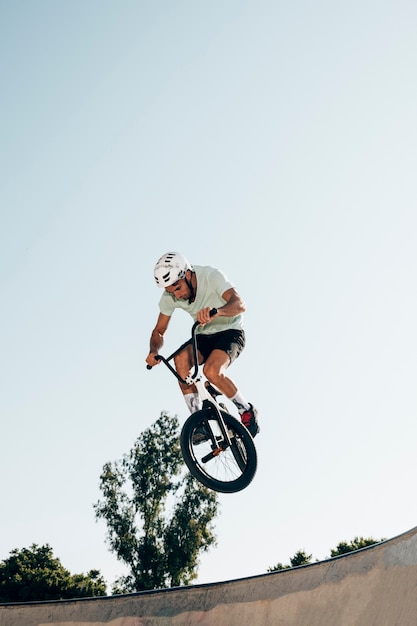 Bezpłatne zdjęcie młodego człowieka kolarstwo w skatepark niskiego kąta strzale