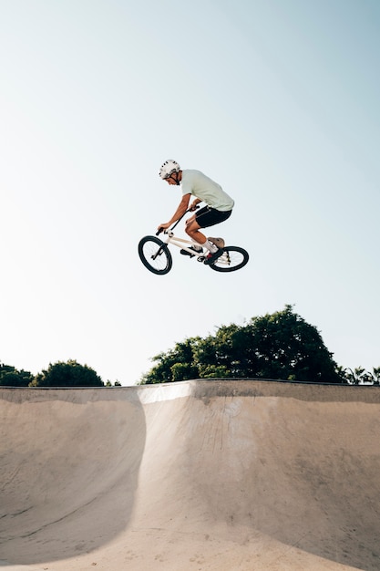 Bezpłatne zdjęcie młody człowiek jedzie bmx bicykl na rampie