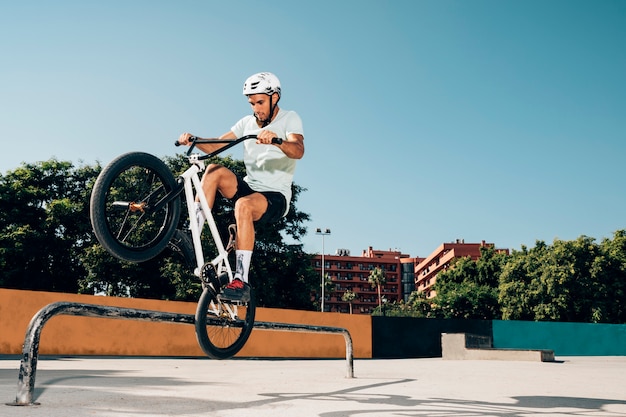 Bezpłatne zdjęcie nastoletni jeździec bmx wykonujący sztuczki w skateparku