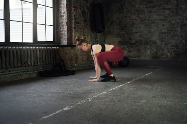 Pełny strzał kobieta robi burpees w pomieszczeniu