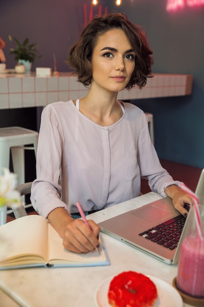 Portret dziewczyny pisać na maszynie na laptopie i pisze notatkach