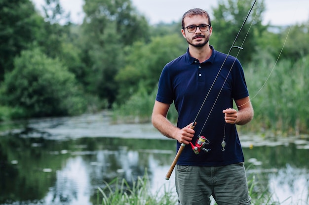 Portret uśmiechnięty mężczyzna mienia połowu prącie blisko jeziora