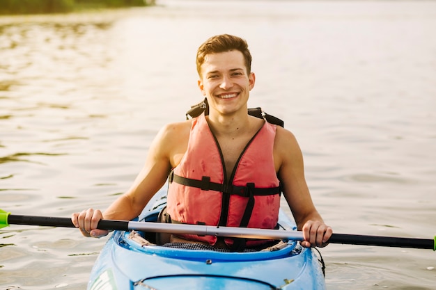 Bezpłatne zdjęcie portret uśmiechnięty młody człowiek kayaking nad jeziorem