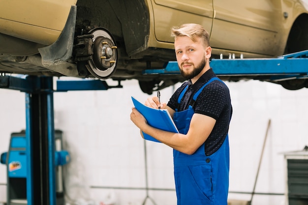 Przystojny technik pracuje przy samochodowym warsztatem