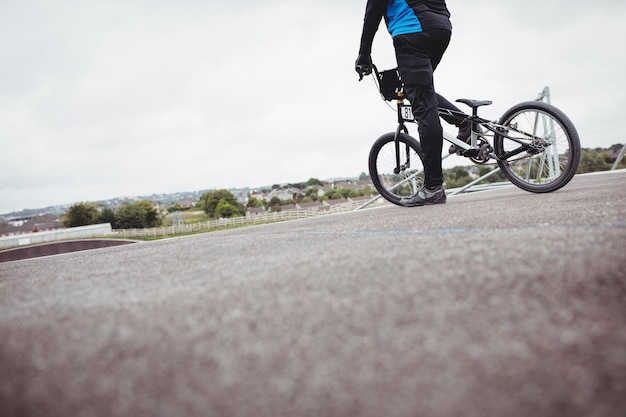 Bezpłatne zdjęcie rowerzysta stojący z rowerem bmx na rampie startowej