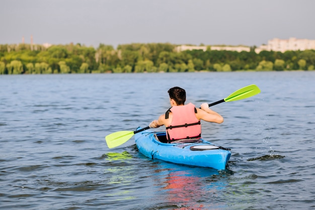 Bezpłatne zdjęcie tylni widok mężczyzna używa paddle dla kayaking