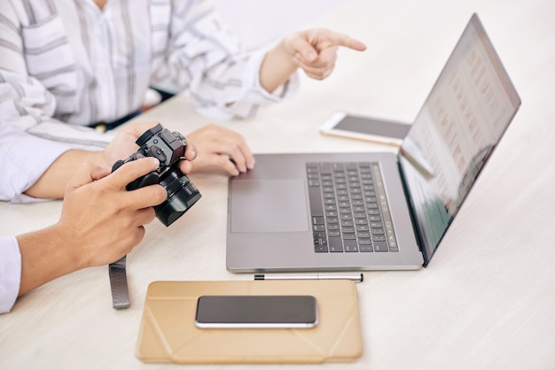 Bezpłatne zdjęcie współpracujący fotografowie z gadżetem przy biurku