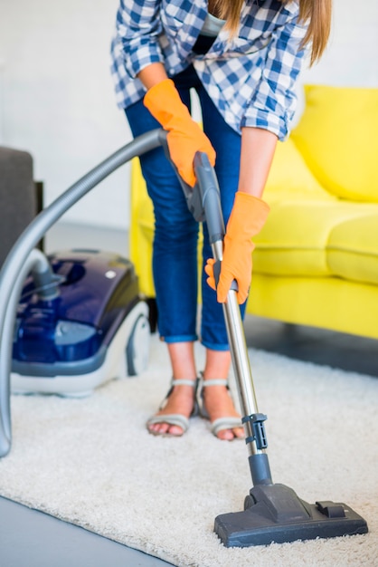 Zakończenie kobiety ręki cleaning dywan z próżniowym cleaner