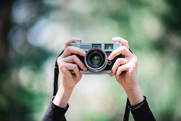 Bezpłatne zdjęcie zbliżenie i selektywna ostrość ręce kobiety profesjonalny fotograf trzymający aparat cyfrowy do robienia zdjęć w przestrzeni kopii lasu przyrody