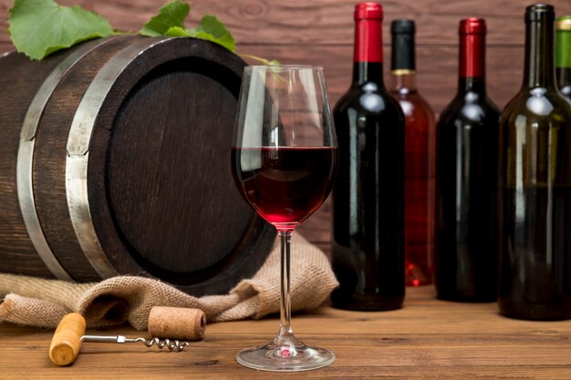 Botte di legno con bottiglie e bicchieri di vino