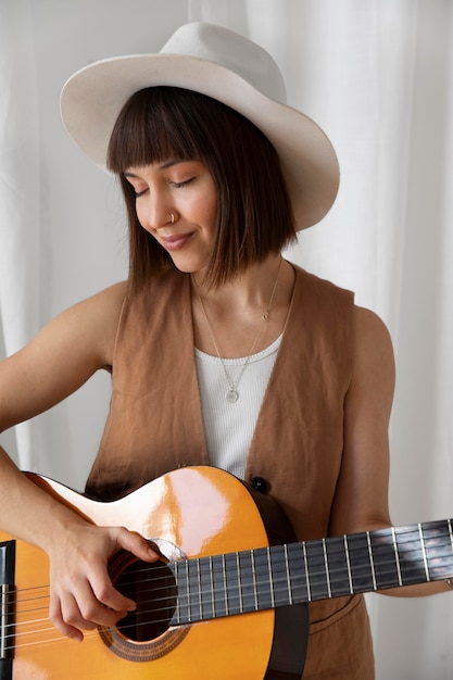 Carina giovane donna che suona la chitarra al chiuso