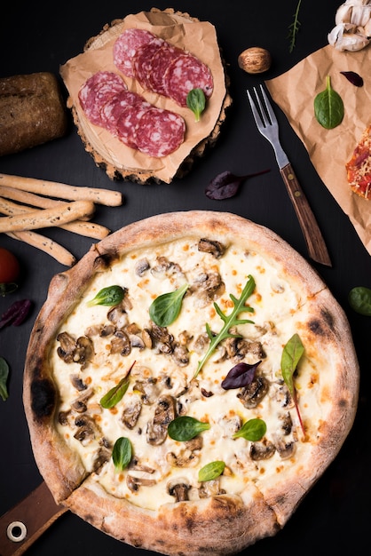 Foto gratuito close-up di pizza ai funghi; fette di peperoni; grissini e forchetta sul bancone