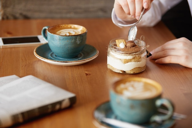 Foto gratuito colpo del primo piano delle mani della donna che mangia il dessert dolce con un cucchiaio