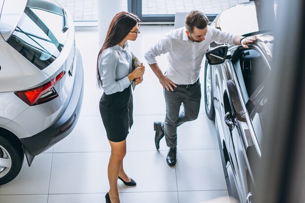 Commesso e donna che cercano un&#39;auto in uno showroom di automobili