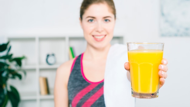 Defocussed giovane donna che offre il bicchiere di succo