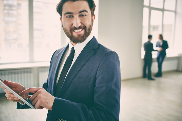 Foto gratuito dipendente barbuto lavorare con tavoletta