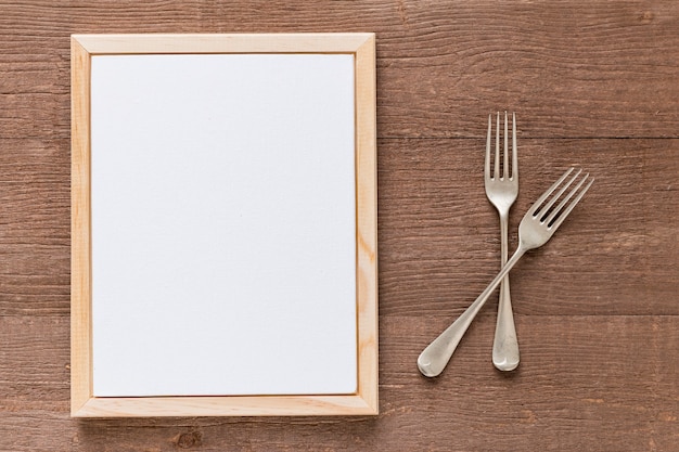 Foto gratuito disposizione piana della carta in bianco del menu con la coltelleria su superficie di legno