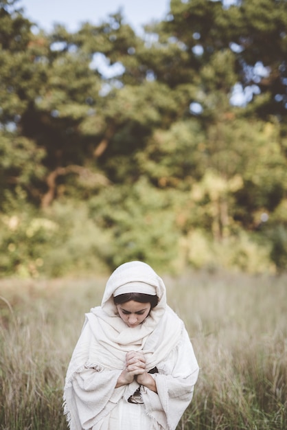 Foto gratuito donna che indossa un abito biblico e prega mentre guarda in basso