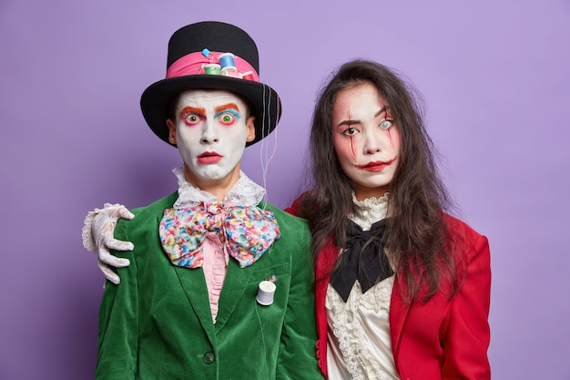 Foto gratuito due amici vestiti con costumi di carnevale di halloween si abbracciano e hanno relazioni amichevoli indossano un trucco spettrale festeggiano le feste isolate sul muro viola