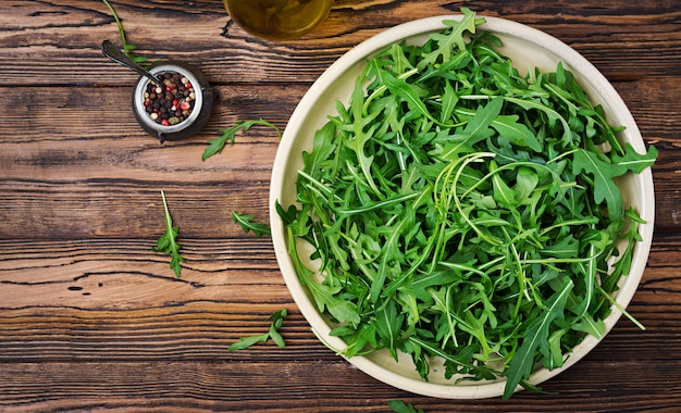 Foto gratuito foglie fresche di rucola in una ciotola su un fondo di legno. disteso. vista dall'alto