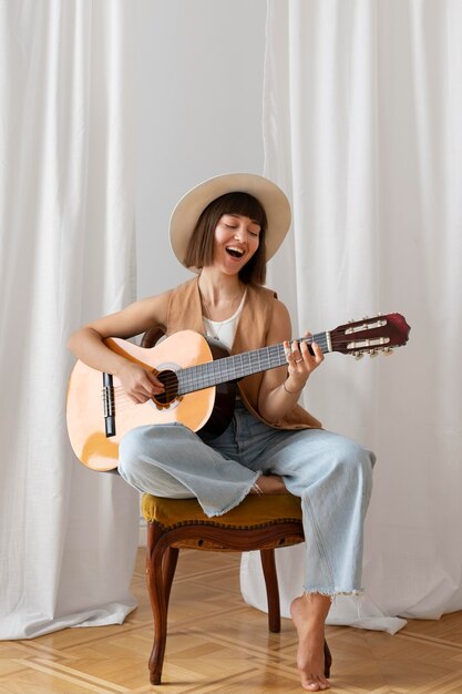 Giovane donna che suona la chitarra al chiuso