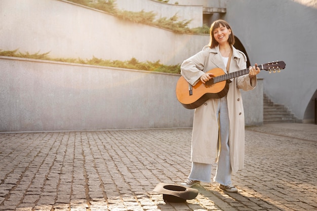 Giovane donna che suona la chitarra all'aperto con spazio di copia